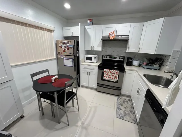 a kitchen with stainless steel appliances kitchen island a table chairs in it and wooden floors