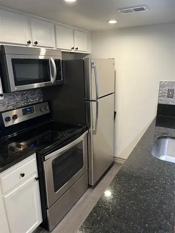 a bathroom with a granite countertop sink and white cabinets