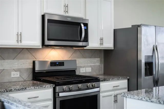 a kitchen with stainless steel appliances granite countertop a stove microwave and refrigerator