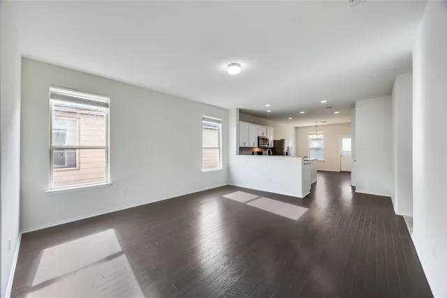 a view of a big room with wooden floor and kitchen