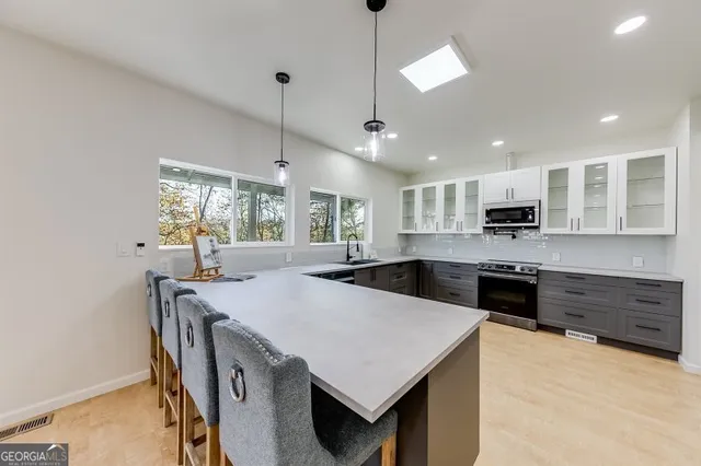 a large kitchen with kitchen island a stove a sink a dining table and chairs