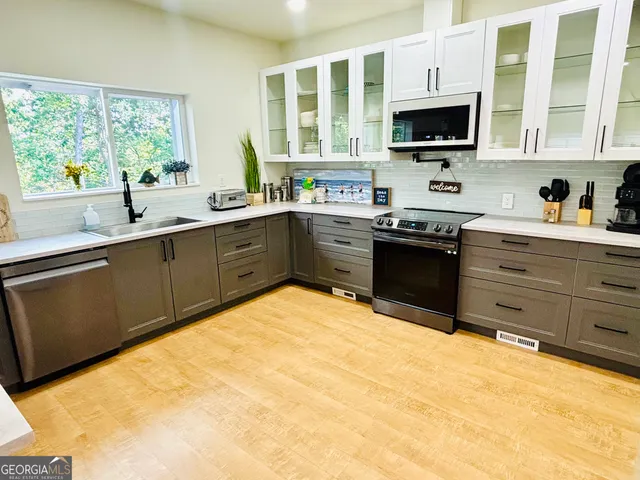 a kitchen with stainless steel appliances granite countertop a stove top oven a sink dishwasher a dining table and chairs