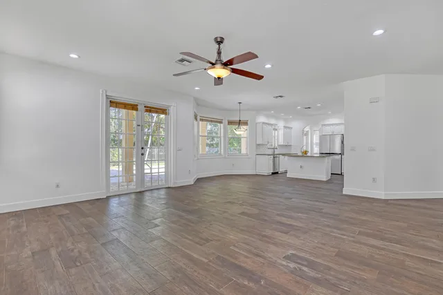 a view of an empty room with window and wooden floor