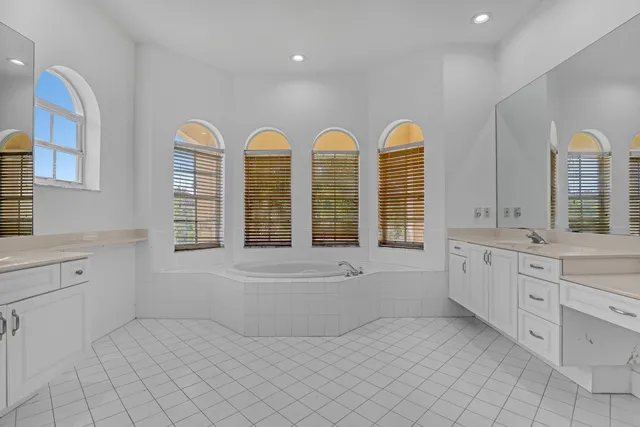 a bathroom with a tub a double vanity sink a window and a mirror