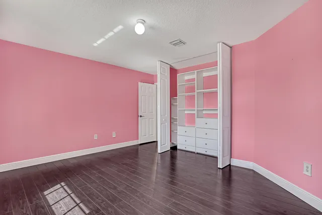 a view of an empty room with wooden floor and windows
