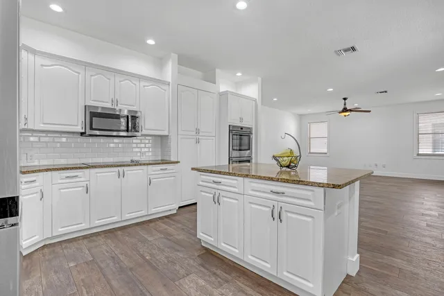a kitchen with kitchen island white cabinets appliances and a sink