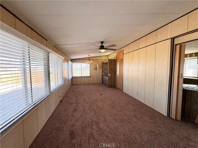 an empty room with ceiling fan and windows