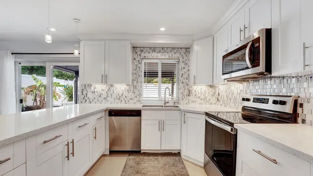 a kitchen with stainless steel appliances granite countertop a stove a sink and a microwave