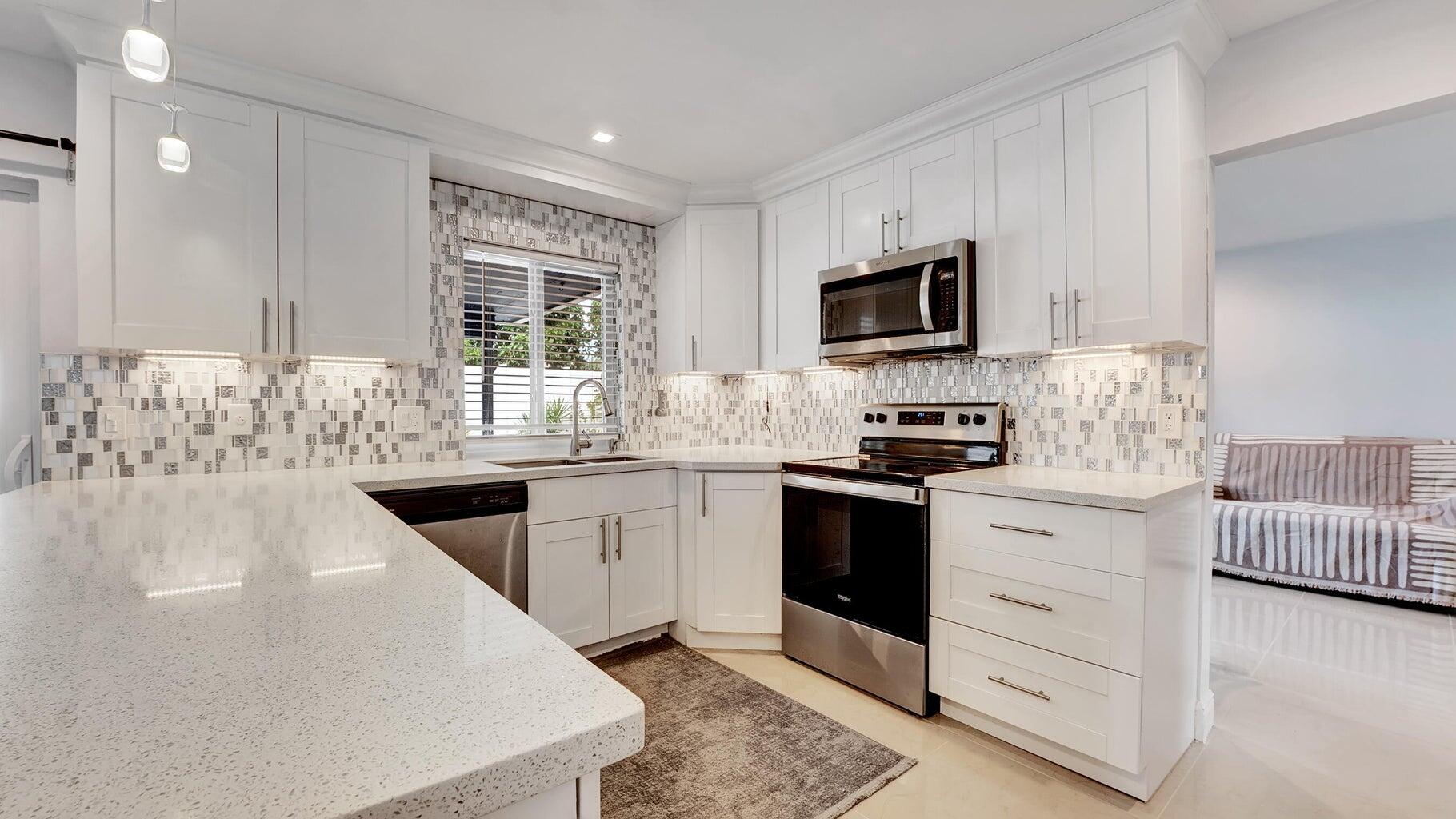 2941 Angler Drive Delray Beach, FL 33445 - Photo 16 of 34 a kitchen with stainless steel appliances granite countertop a stove a sink and a microwave