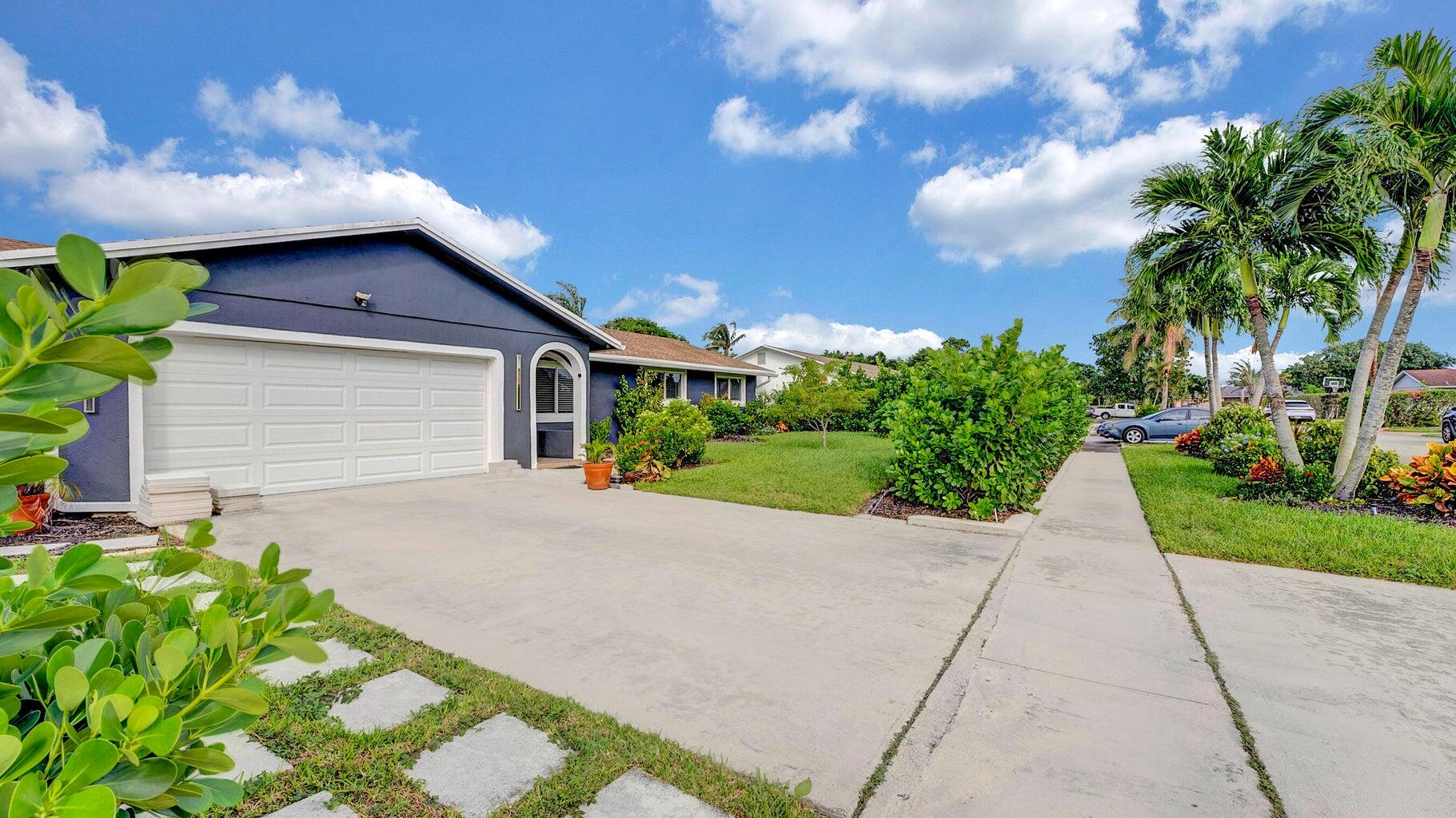 2941 Angler Drive Delray Beach, FL 33445 - Photo 2 of 34 a yellow house with flower garden in front of it