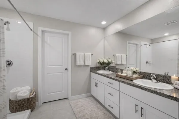 a spacious bathroom with a double vanity sink a mirror and a bathtub
