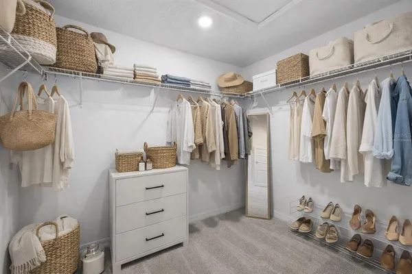 a view of walk in closet with clothes and shoes