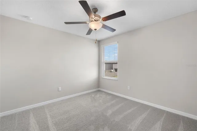 an empty room with a ceiling fan and window