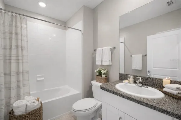 a bathroom with a granite countertop sink toilet mirror and shower
