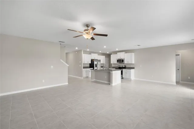 a view of an empty room with kitchen view and a window