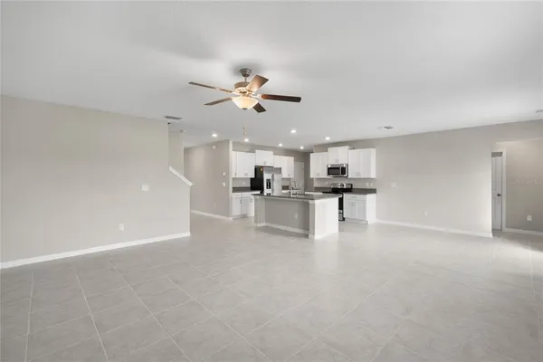 a view of an empty room with kitchen view and a window