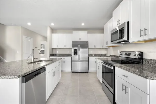 a kitchen with stainless steel appliances granite countertop a sink stove oven and refrigerator