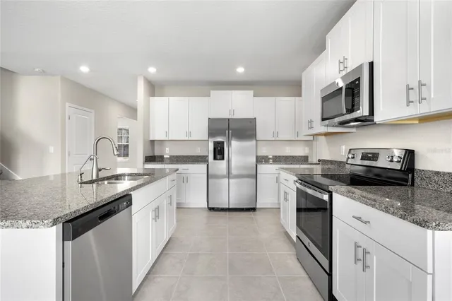 a kitchen with stainless steel appliances granite countertop a sink stove oven and refrigerator
