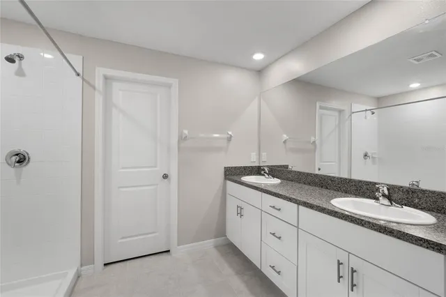 a spacious bathroom with a granite countertop sink a mirror and a shower