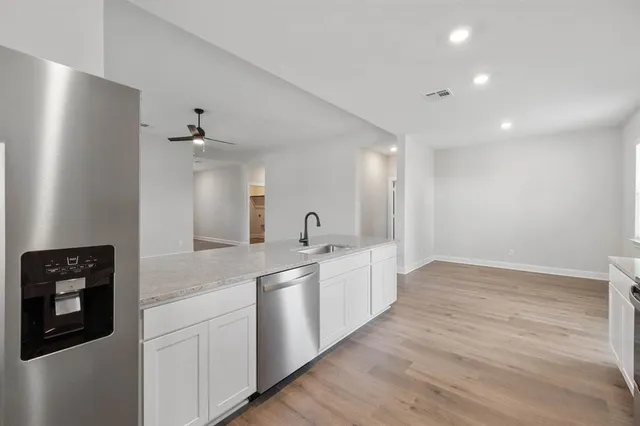 a large white kitchen with a sink and dishwasher