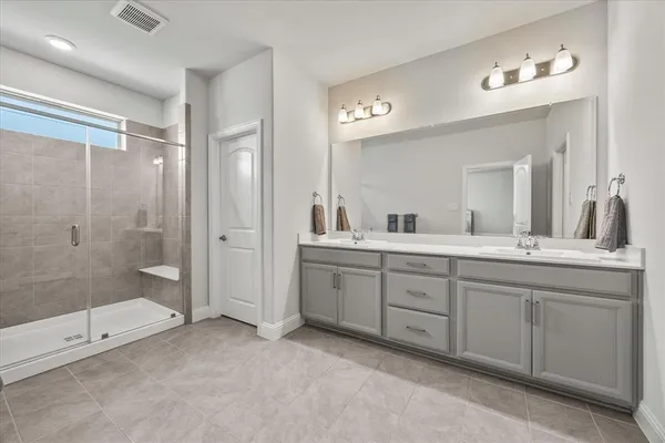 a spacious bathroom with double sink shower and two mirror