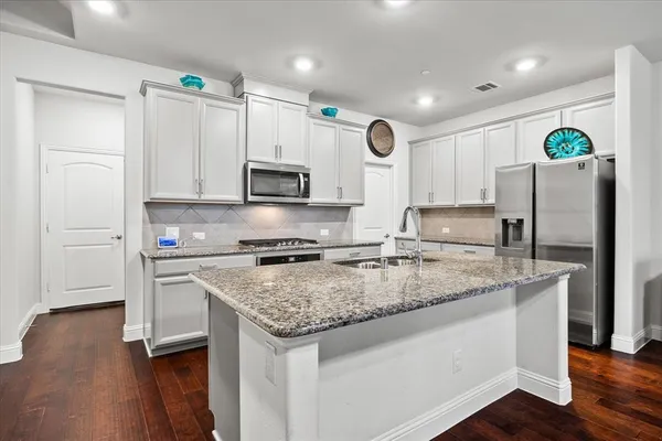 a kitchen with stainless steel appliances granite countertop a refrigerator stove microwave and sink