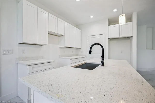 a kitchen with kitchen island a sink a stove and cabinets