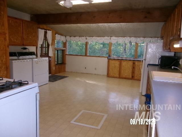 31997 2nd Fork Road Ola, ID 83657 - Photo 12 of 47 Kitchen area featuring wood beam ceiling accents, wood-finish cabinetry, a window-lined wall, and a built-in sink with countertop
