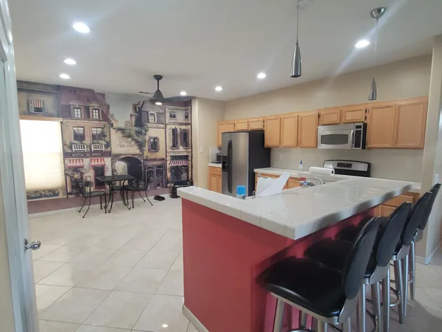 a kitchen with stainless steel appliances kitchen island granite countertop a table chairs and a refrigerator