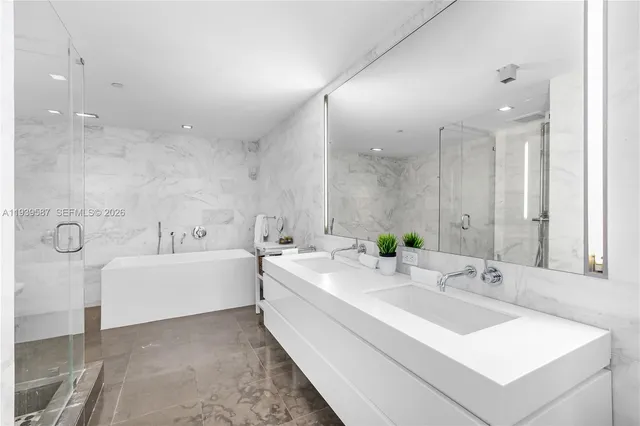 a bathroom with a double vanity sink mirror and bathtub