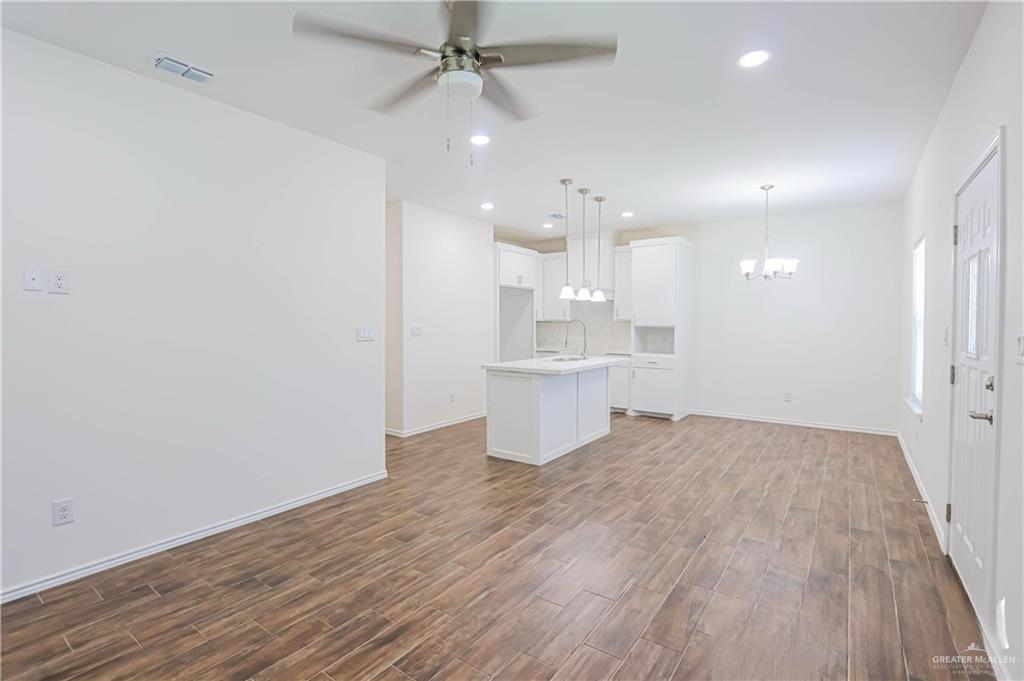 1046 Hidalgo Street Mercedes, TX 78570 - Photo 5 of 21 an empty room with wooden floor and kitchen view
