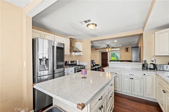 a kitchen with a stove a sink a kitchen island with stainless steel appliances wooden floor and cabinets
