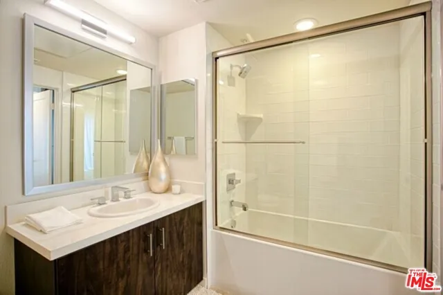 a bathroom with a shower sink vanity and mirror