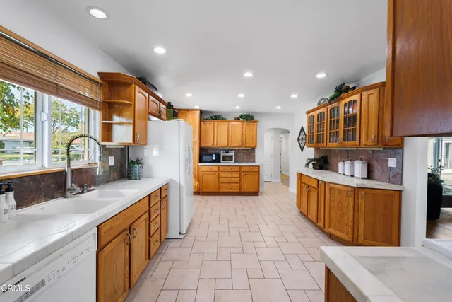 a large kitchen with stainless steel appliances granite countertop a large counter top a stove a sink and a refrigerator