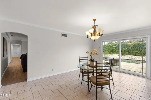 a view of a dining room with furniture a chandelier and large windows