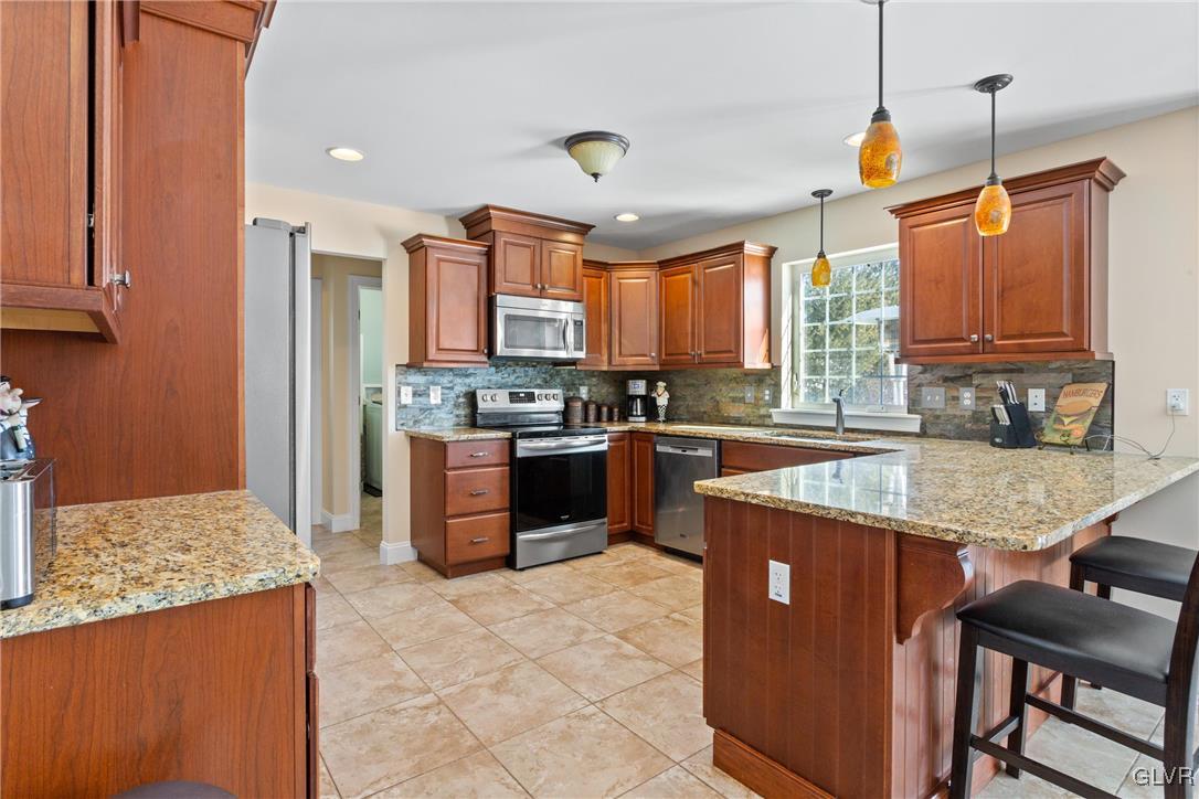 127 Fox Ridge Nazareth, PA 18064 - Photo 9 of 48 a kitchen with stainless steel appliances granite countertop a stove top oven a sink dishwasher and a refrigerator with wooden cabinets