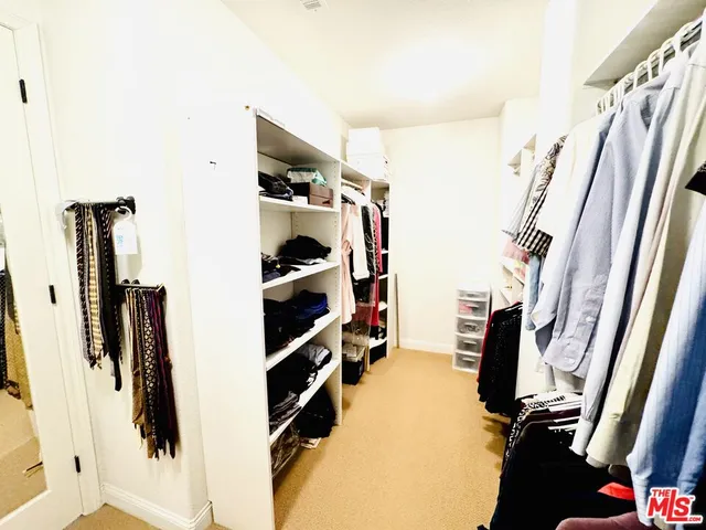 a view of walk in closet with clothes and shoes