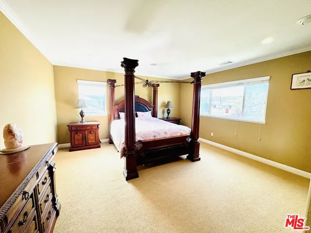 a bedroom with a bed and large windows