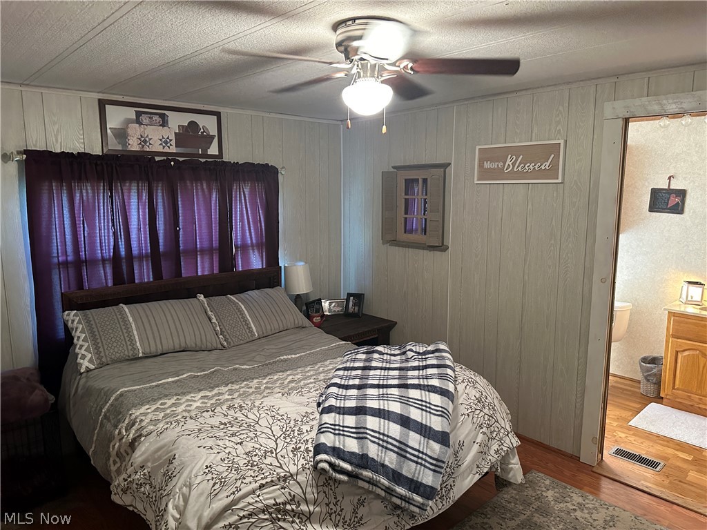 4041 Gray Road Kimbolton, OH 43749 - Photo 25 of 32 Bedroom featuring a textured ceiling, ceiling fan, ensuite bathroom, and hardwood / wood-style flooring