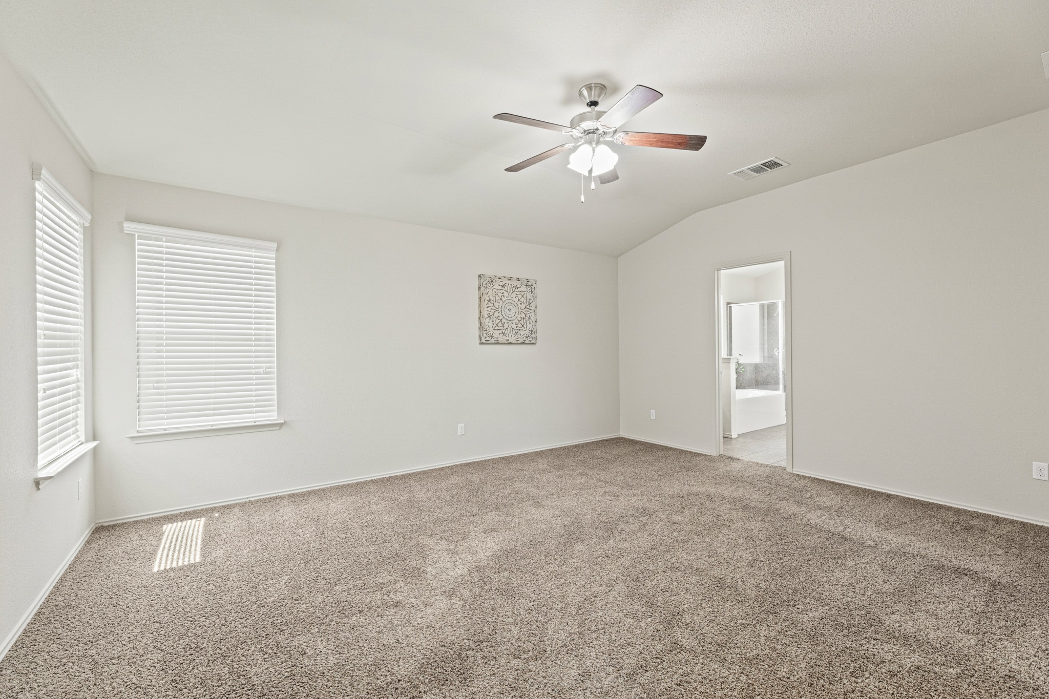 232 Geode Lane Jarrell, TX 76537 - Photo 18 of 39 The primary bedroom layout features plush carpeting and vaulted ceilings with large windows.
