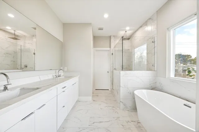 a bathroom with a tub a sink shower and mirror