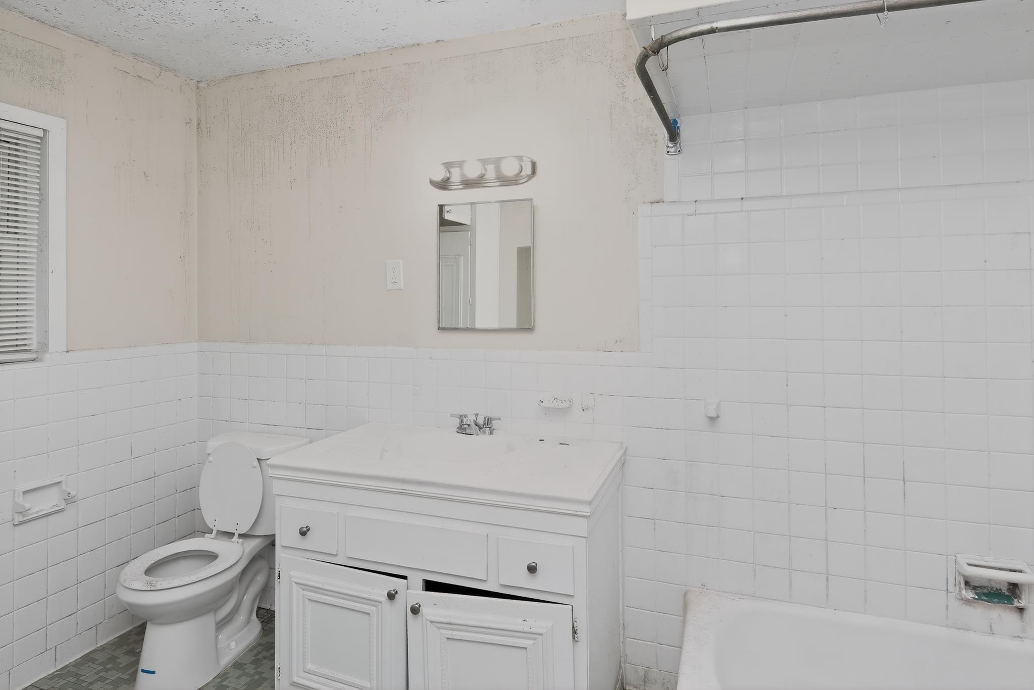 1403 Old Hickory Road Memphis, TN 38116 - Photo 25 of 31 Bathroom featuring a white vanity with integrated sink, white tiled walls, a toilet, a bathtub, and a window with blinds