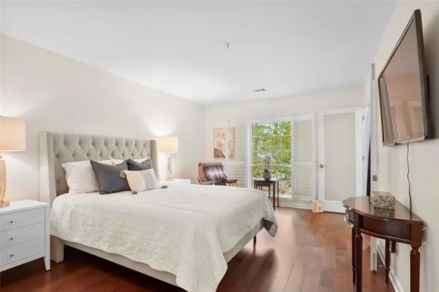 a bedroom with a bed a large window and wooden floor
