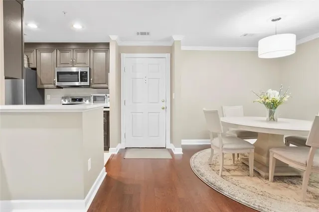 a kitchen with kitchen island stainless steel appliances a refrigerator a sink a stove a dining table and chairs