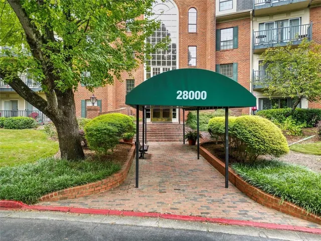 a view of a brick house with a yard and table and chairs under an umbrella