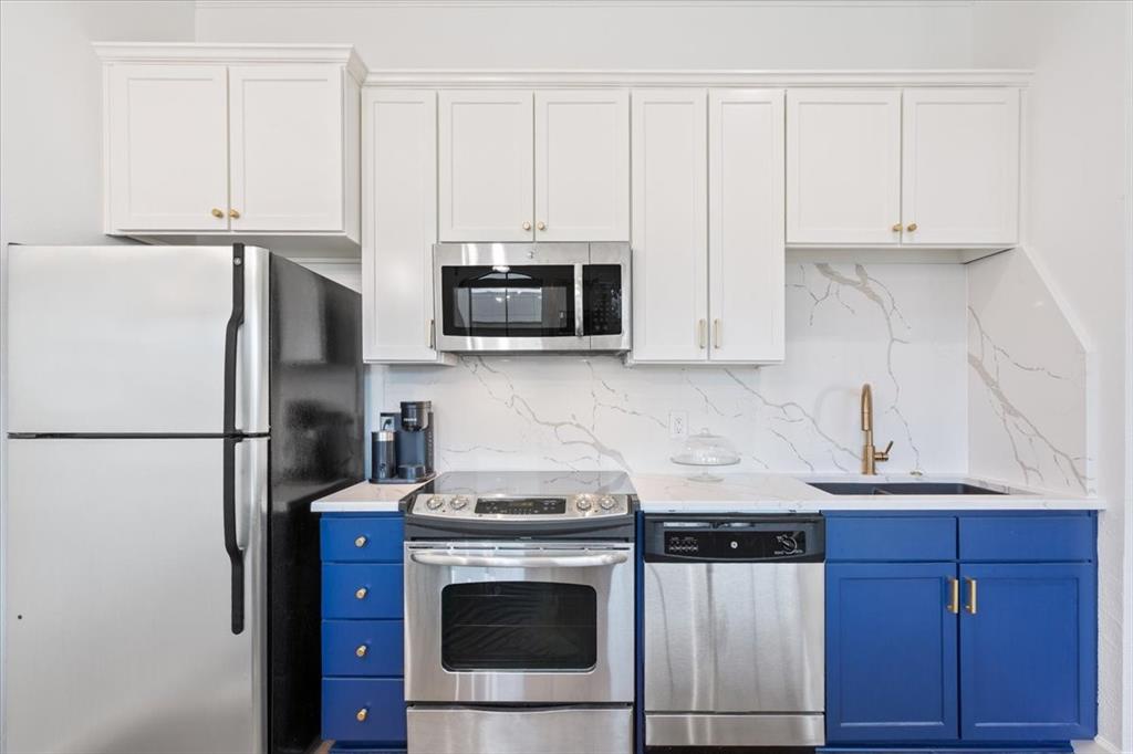 330 Austin Avenue, Unit 318 Waco, TX 76701 - Photo 16 of 22 Kitchen with stainless steel appliances, white cabinetry, blue cabinets, decorative backsplash, and light stone countertops