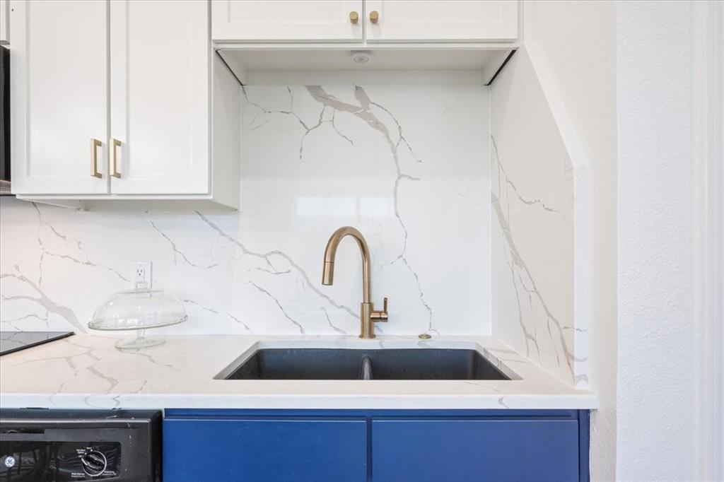 330 Austin Avenue, Unit 318 Waco, TX 76701 - Photo 19 of 22 Kitchen featuring decorative backsplash, light stone countertops, blue cabinetry, dishwashing machine, and white cabinets