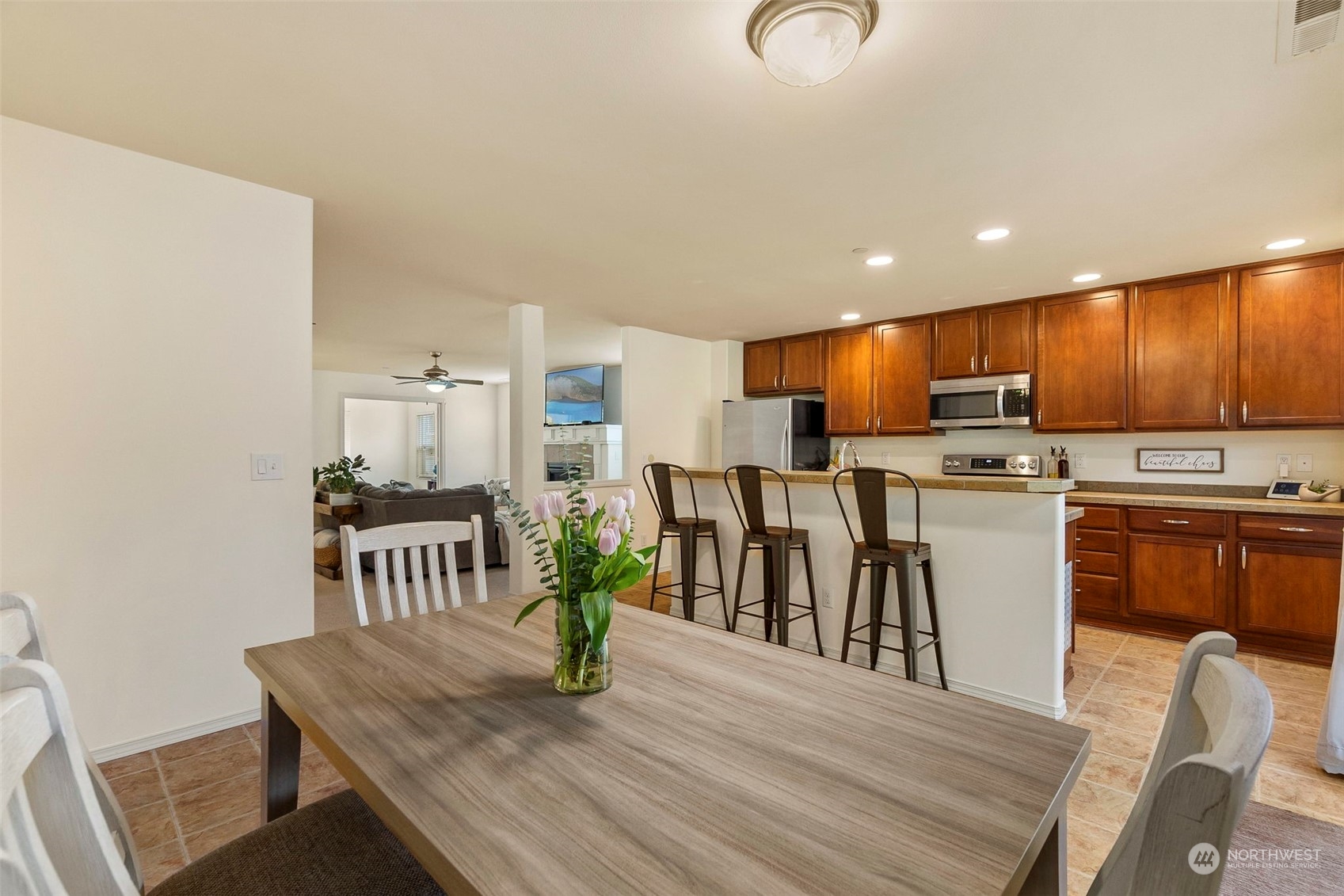 1328 Foreman Road DuPont, WA 98327 - Photo 12 of 37 a open kitchen with granite countertop a refrigerator a stove a sink a dining table and chairs with wooden floor