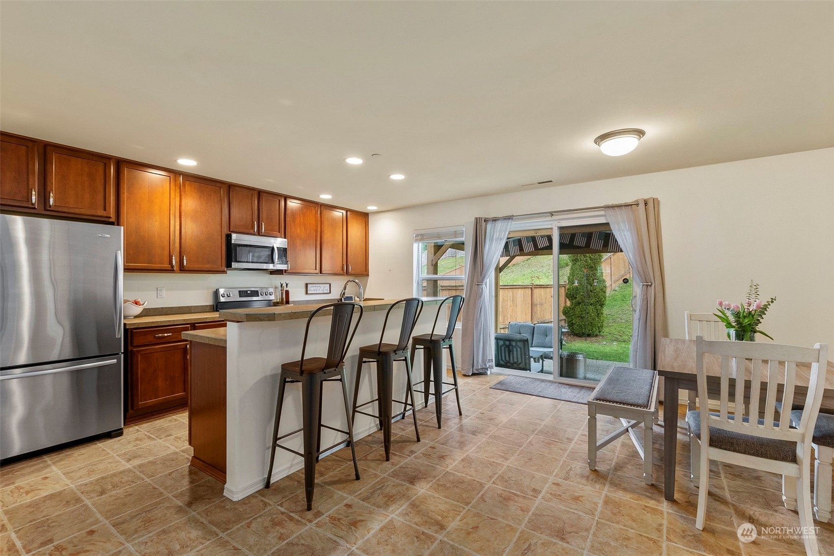 1328 Foreman Road DuPont, WA 98327 - Photo 10 of 37 a kitchen with stainless steel appliances granite countertop a refrigerator a stove a sink a dining table and chairs with wooden floor
