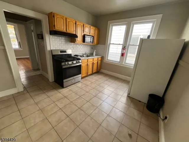 a kitchen with stainless steel appliances a sink a stove top oven a counter space and a window